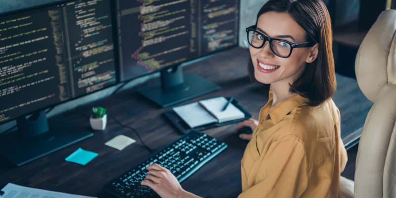 A cheerful skilled girl delivering productive work at an indoor workplace workstation.