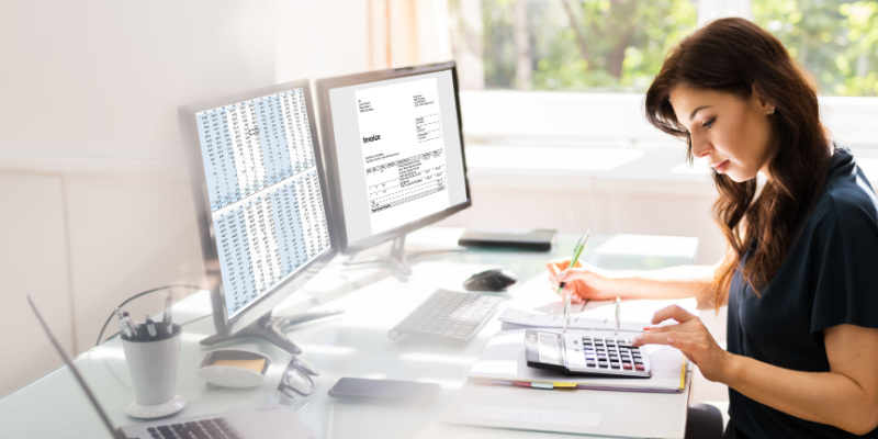 An employee using a dual screen in an office illustrates the employee's time tracking system.